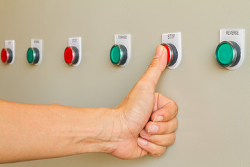 Thumb touch on red stop switch on control panel for machine controller.