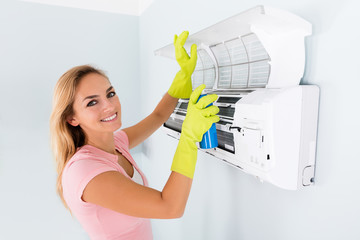 Woman Cleaning The Air Conditioner