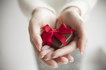 The woman presents a heart-shaped chocolate
