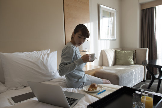 A young lady is drinking coffee at a hotel on a business trip