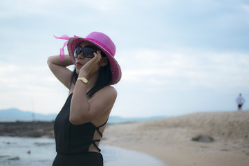 Sexy woman with black dress posing on the beach