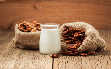 Milk in glass bottles and almonds in bags on the old wooden floor.