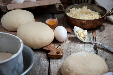 Khachapuri in process. Dough and filling on the wooden board.