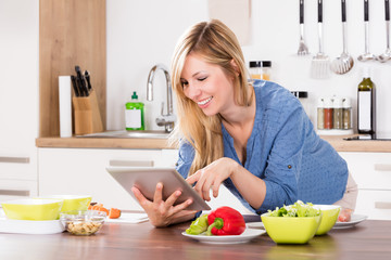 Obraz na płótnie Canvas Smiling Woman Using Digital Tablet In Kitchen