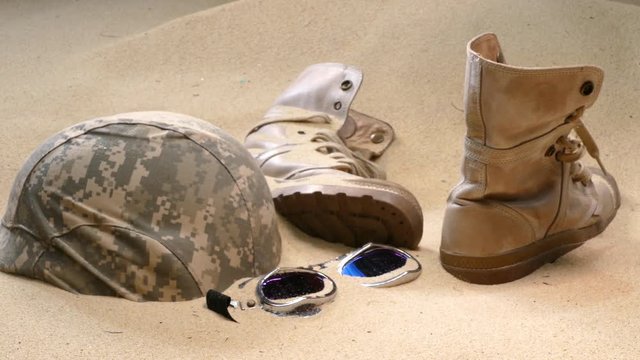 soldier hat  boots and sand glass in the desert
Wreck bulletproof helmet Military boots and goggles sand in the desert It sank in the sand