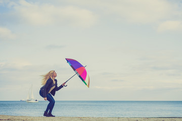 Woman jumping with colorful umbrella on beach