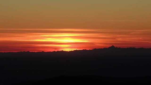 Fiery sunset from mountain pick with thin glazes in the sky evening. Fall season. Orobie alps. Rena pick. Bergamo Italy. In the distance the Monviso.