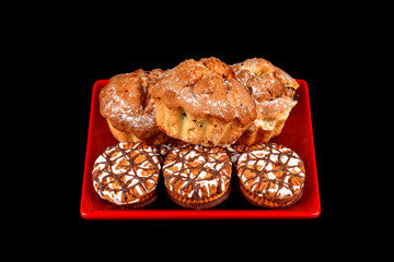 Cake and chocolate chip cookies on a red plate on a black background.