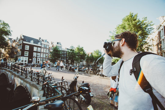 Tourist photographer takes selfie photo in Amsterdam, Netherlands. Tourist walks near canals on excursion and take photos for his blog.