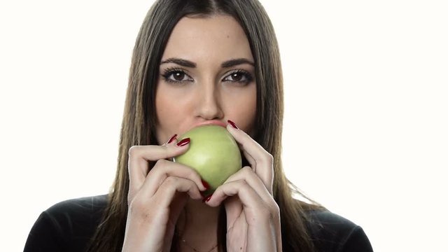 Pretty brunette young woman holding with two hands an apple and give a bite 