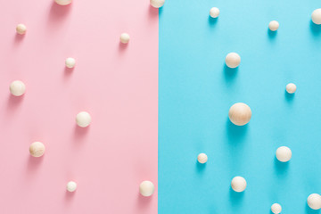 Wooden craft spheres make pattern on blue and pink paper in halves