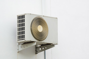 Air conditioner compressor unit on white wall.