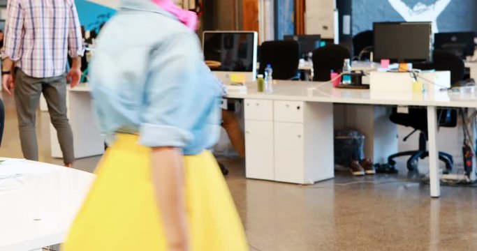 Businessman using hoverboard while coworkers working 