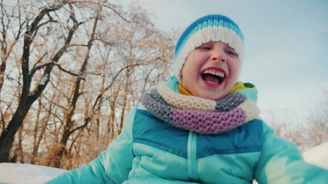 Cool the child goes on a sledge, making funny faces, enjoys winter.