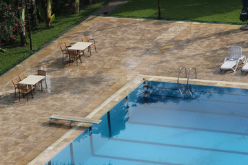 A swimming pool with tables and chairs around
