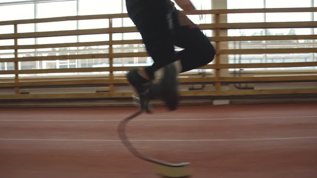 Low section tracking of amputee sprinter with prosthetic leg training running on track at indoor stadium 