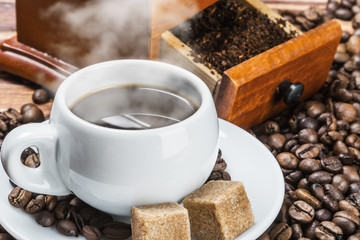 cup of warm coffee and coffee grinder on a wooden table