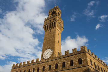 Fragment of clock tower of the Old Palace with blue sky. Tuscany. Italy.