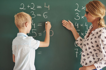 Student boy with chalk next to the chalkboard