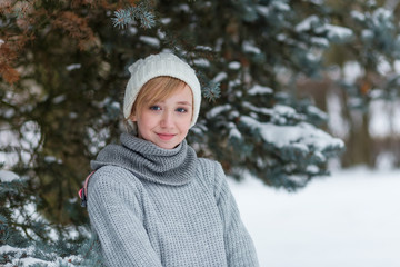 Beautiful girl in a white hat and mittens in the winter snowy fo