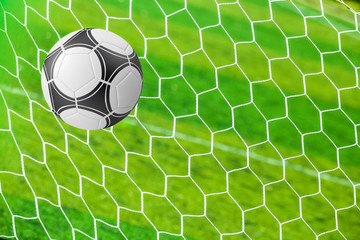 soccer ball in goal net with green grass
