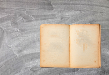 Open old brown book on Blackboard background