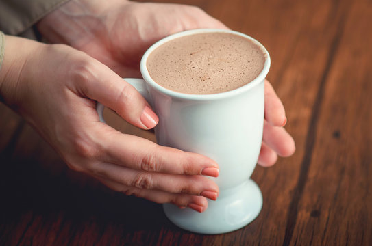 Female hands tenderly holding cup of cacao