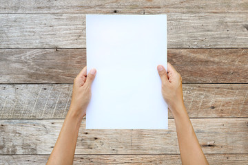 Woman hand holding sheet of paper isolated on wood plank background.