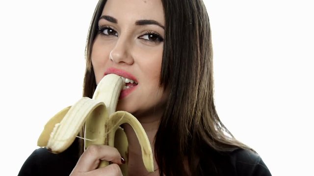 Brunette beautiful woman with big fleshy lips eat gently a banana