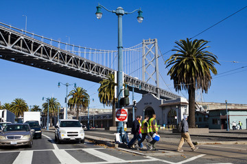 Workers crossing street in San Francisco under Oakland Bridge