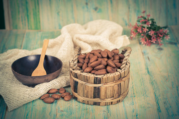 Almonds in brown bowl on textured wooden background