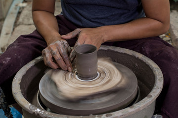 Hands of potter do a clay cup