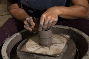 Hands of potter do a clay cup