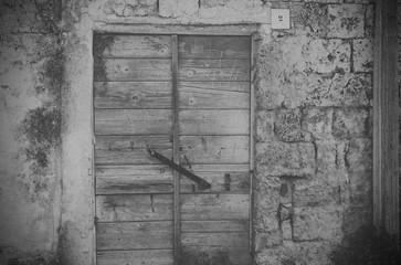 The door of an abandoned house. Ruins, decay, loneliness. Old-print black-and-white style.
