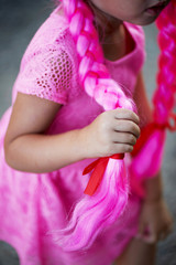Children handle holds a braid of pink hair. Festive