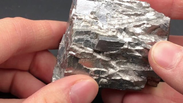 Female fingers show a stone of Galena or lead glance, a natural mineral form of lead sulfide.