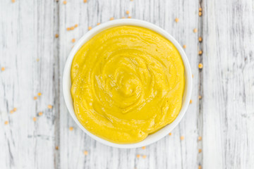 Mustard (selective focus) on vintage wooden background