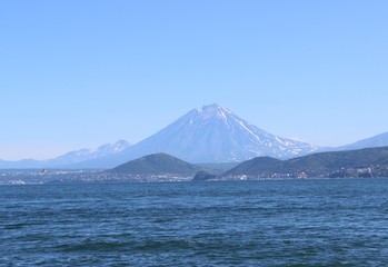 Ocean waves on a sunny day with a volcano on the horizon