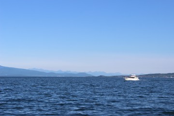 Fototapeta premium Lonely boat in the middle of the ocean, a mountain range on the horizon