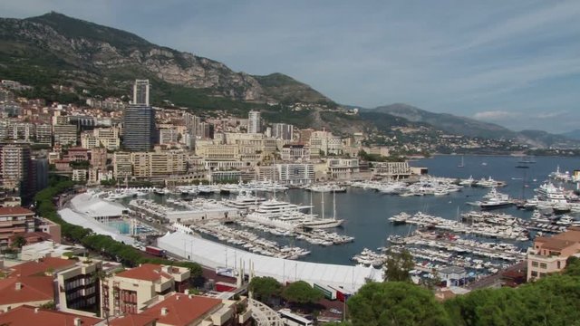 Pan across an elevated view over the the port of Monte Carlo in Monaco. Cruise ships are anchored in the bay