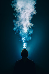 The man smoke an electronic cigarette on the background of bright light - obrazy, fototapety, plakaty