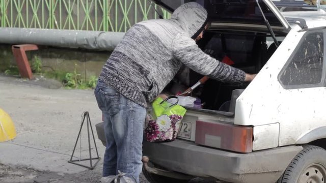 Man cleans in the trunk of a white car