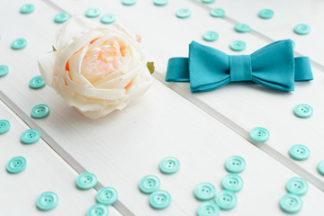 White rose, button and tie on a white wooden background