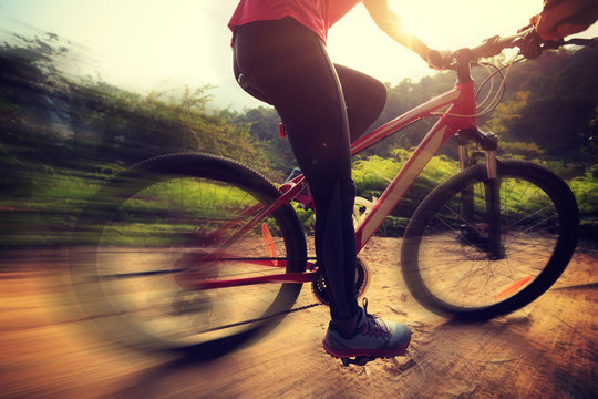 young woman riding mountain bike on forest trail