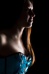 portrait of sexy young woman in corset with lacing posing on a dark background