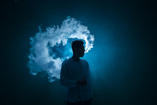 The man smoke an electrical cigarette on the dark background