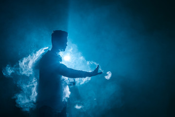 The man smoke an electrical cigarette with a ring on the dark background