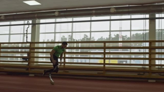 PAN of amputee athlete with artificial limb running on track in slow motion
