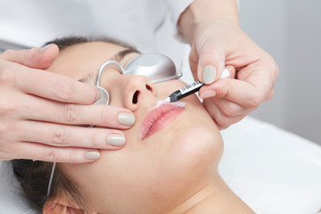 Obraz na płótnie Canvas Beautician Giving Epilation Laser Treatment To Woman On lips