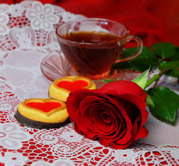 Fototapeta na wymiar Red rose with hearts cookies and a cup of tea. Valentine's Day, romantic still-life.